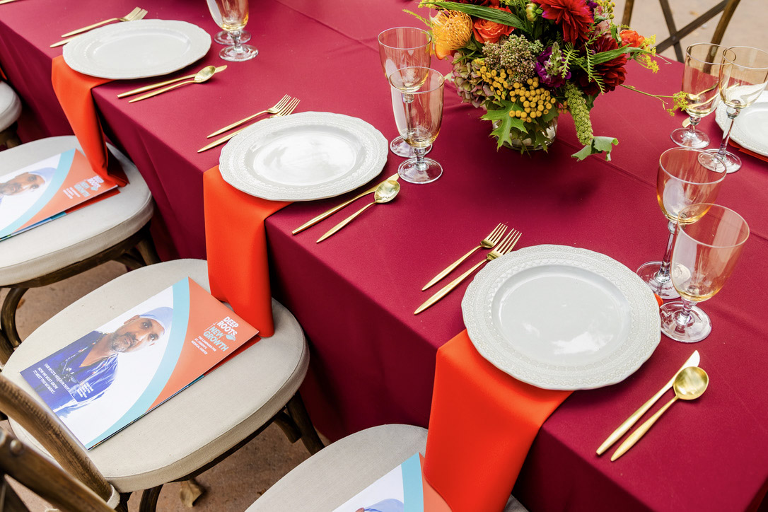 Close view of plates, glasses, gold flatware and orange linen